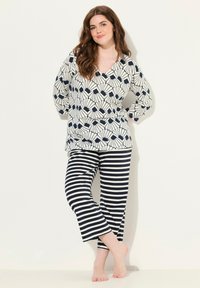 Ensemble de loungewear comprenant un haut blanc avec un imprimé floral marine et un pantalon rayé bleu marine et blanc. Tissu doux, coupe décontractée, manches longues.
