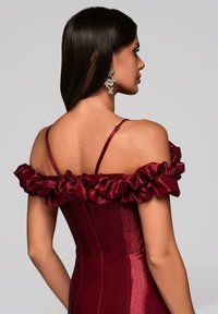 Bordowa sukienka z falbaniastymi rękawami odsłaniającymi ramiona, dopasowanym gorsetem i gładką fakturą. Srebrne kwiatowe kolczyki dopełniają całość.
