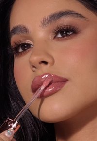 Lipgloss in een doorzichtige tube met een roségouden accent. Glanzende, lichtroze tint wordt op de lippen aangebracht met een doe-foot applicator. Soepele textuur.