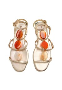 Sandalias doradas con tiras que presentan tres grandes piedras ovaladas de colores rojo y naranja. Acabado metálico suave con correas ajustables en el tobillo.