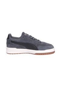Sneaker in suede grigio con un accento in pelle nera, suola intermedia bianca e suola esterna in gomma color caramello. I lacci passano attraverso sei occhielli.