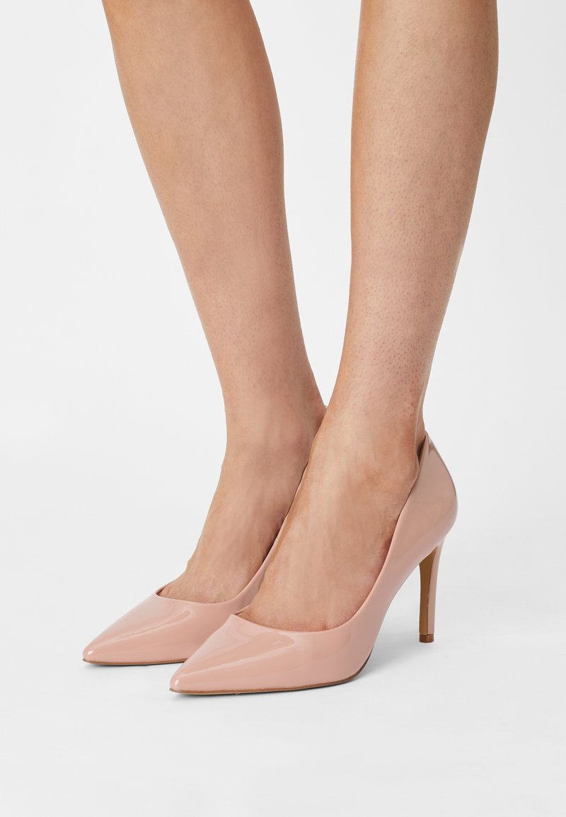 Chaussures à talons aiguilles en cuir verni rose, à bout pointu, avec un design élégant et un talon stiletto fin, présentant une découpe basse sur les côtés pour plus d'élégance.