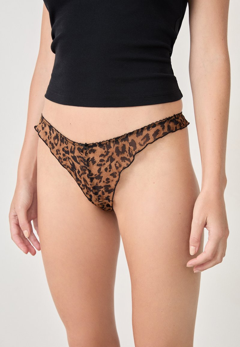 Tanga de leopardo semitransparente en marrón y negro con un borde con forma de ondas y delicados detalles. Ligera, con un diseño de cobertura mínima.