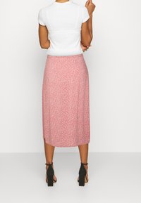 Vaaleanpunainen kukallinen midi-hame, joka on valmistettu kevyestä kankaasta, jossa on valkoisia kukkakuviota, sileä pinta ja hienovarainen A-linjainen muoto.