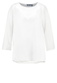 Blusa bianca a maniche lunghe in tessuto leggero con scollo a V e dettagli in pizzo sulle spalle; vestibilità rilassata e texture leggermente trasparente.