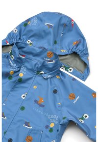 Sinine veekindel jope kapuutsi ja erinevate värviliste spordimotiividega mustriga, mis hõlmavad palle ja rulalaudu, sileda tekstuuriga.