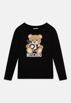 Chemise noire à manches longues avec un ourson tenant le mot "TOY" et "MOSCHINO" imprimé en dessous de l'ourson sur le devant.