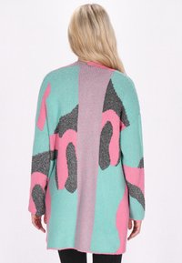 Cardigan colorato con una combinazione di motivi astratti turchesi, rosa e neri. Maniche lunghe, texture morbida e vestibilità rilassata.