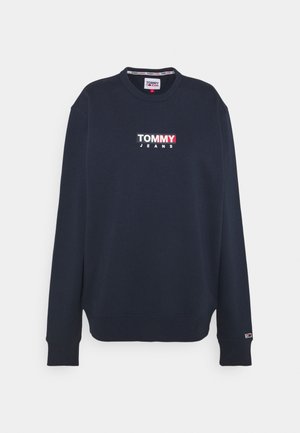Sudadera azul marino con cuello redondo, puños y dobladillo acanalados. Presenta el logo frontal "TOMMY JEANS" en blanco y rojo. Textura de tela suave.