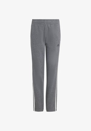 Šedé sportovní kalhoty s texturovanou tkaninou, elastickým pasem a bílými bočními pruhy. Na levé noze je černé logo Adidas.