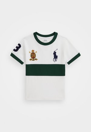 Balta kokvilnas T-kreklu ar zaļām svītrām, ar jūras zilā krāsā polo spēlētāja logotipu, izšūtu kroni un "20" simbolu, īsām piedurknēm.