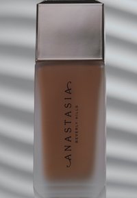 Flüssige Foundation in einer frostigen Glasflasche mit einem eleganten silbernen Deckel. Enthält das Logo "ANASTASIA BEVERLY HILLS" in schwarzer Schrift.