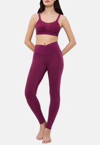 Soutien-gorge de sport violet et leggings taille haute en tissu extensible, présentant un design texturé et des détails de coutures contrastées.