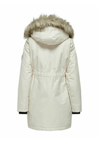Parka bianca impermeabile con cappuccio bordato in pelliccia, vita elastica e polsini in maglia nera. Tessuto liscio con un leggero design trapuntato.