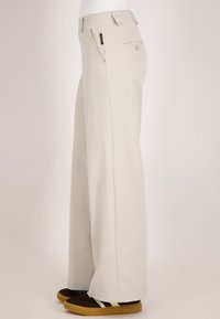 Lichtbeige wijde broek van een zachte stof, met achterzakken en een discreet logo-label op de tailleband.