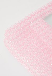 Rožinės karoliukų aksesuaras su tekstūruota danga, kuriame glaudžiai išdėstyti aiškūs ir nepermatomi šešiakampiai karoliukai.