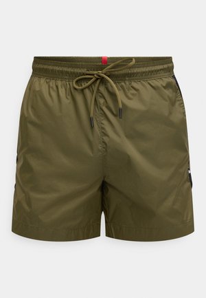 Olive green swim shorts made from lightweight material, featuring an elastic waistband with drawstring, side pockets, and black accents.