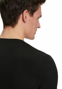 Schwarzes, geripptes T-Shirt mit rundem Halsausschnitt und kurzen Ärmeln, das eine Nahaufnahme des Rückens und der Schulter zeigt.