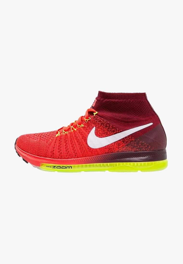 Červené pletené tenisky s vysokým designem kotníku, mají bílé logo Nike Swoosh, žluté tkaničky a zeleně zabarvenou podrážku s označením "Nike Zoom".