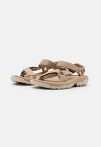 Tan sandals with multiple adjustable straps, a textured footbed, and a thick white rubber sole featuring a patterned tread for traction.