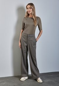 Szary, krótki top połączony z szerokimi spodniami w wzór houndstooth. Jasnobeżowe sneakersy z białymi i taupe akcentami. Gładkie tekstury.