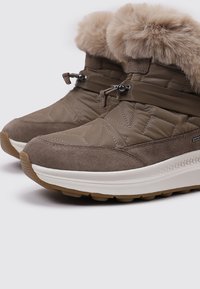 Bottes d'hiver isolées brunes avec une bordure en fausse fourrure, un design matelassé, en matériaux en daim et synthétiques, et une semelle en caoutchouc texturé.