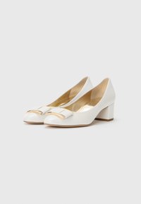 White leather block-heeled shoes with rounded toes, featuring a decorative bow and gold hardware. Smooth texture with a glossy finish.