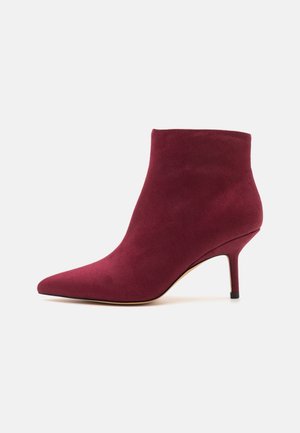 Bottine femme en daim bordeaux avec bout pointu et talon aiguille fin de hauteur moyenne sur fond blanc.