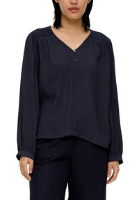 Navyblaue Bluse mit langen Ärmeln, V-Ausschnitt, Knopfverschluss vorne, strukturiertem Stoff und gerafften Schultern für zusätzlichen Detailreichtum.