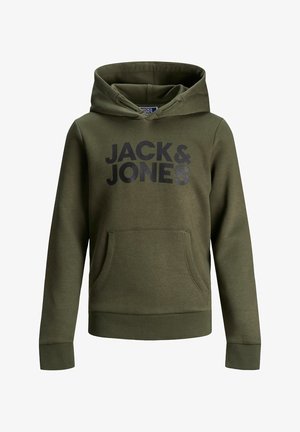 Personne debout les mains dans les poches, portant un sweat à capuche olive Jack & Jones et un pantalon de survêtement assorti, avec des baskets blanches sur un fond gris.