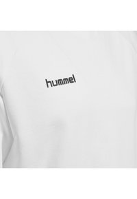 Felpa bianca con maniche raglan e una texture liscia. Presenta un logo "hummel" nero sul petto. Design semplice e minimalista.