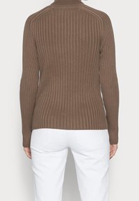 Brauner gerippter Pullover mit langen Ärmeln und hohem Kragen, der ein figurnahes Design zeigt. Die Textur ist glatt mit vertikalen Linien und seitlichen Schlitzen.