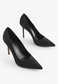 Décolleté neri in suede con punta affilata e tacco stiletto sottile. Superficie liscia, design minimalista e dettagli interni discreti.