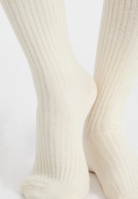 Rippensocken in Cremefarbe aus weichem Material, mit bequemer Passform und nahtlosem Zehendesign sowie dezenten Texturdetaillierungen.