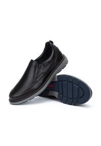Zwarte leren instapschoenen met een gladde afwerking, grijze rubberen zool met een profiel voor grip, en elastische zijpanelen voor gemakkelijk aan- en uittrekken.
