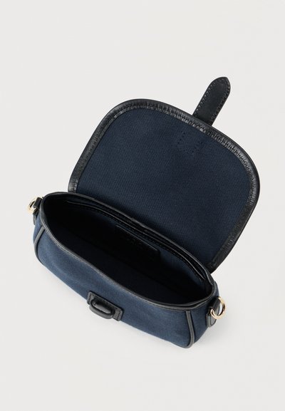 Ναυτικό τσάντα από καμβά με μαύρη δερμάτινη επένδυση, φερμουάρ και μία χειρολαβή στο πάνω μέρος. Το εσωτερικό δεν έχει επιπλέον τσέπες ή διαμερίσματα.