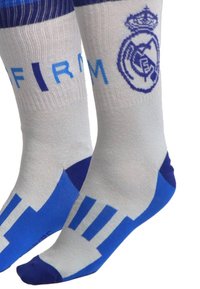 Calze blu e bianche con parte superiore a righe, dotate del logo del Real Madrid in blu e della scritta "FIRM" in azzurro chiaro, con dettagli decorativi.