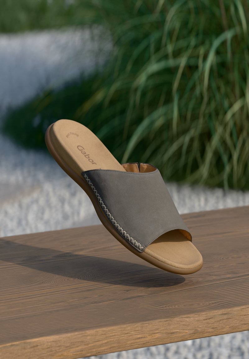 Sandal in pelle grigia con punta aperta arrotondata, caratterizzato da un accento cucito lungo la cucitura e una suola marrone testurizzata.
