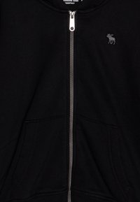 Czarna bluza z kapturem zapinana na zamek, wykonana z miękkiego materiału, z kieszenią typu kangur oraz małym haftowanym logo łosia po lewej stronie klatki piersiowej.