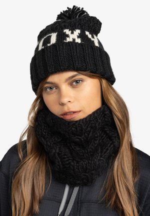 Czarna dziana czapka z białym napisem i pomponem na górze, zestawiona z grubym czarnym dzianym komin z teksturowanym wzorem.