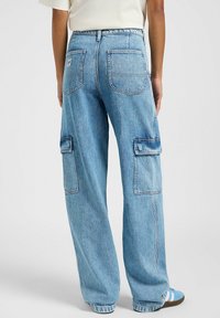 Pantaloni cargo in denim azzurro chiaro con vestibilità rilassata, dotati di due tasche laterali e due tasche posteriori, cuciture a vista e un design a gamba dritta.