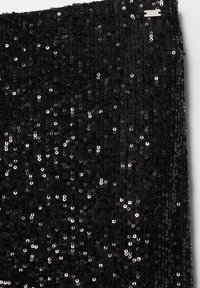 Czarna tkanina z cekinami o gęstym układzie błyszczących, okrągłych cekinów, tworząca teksturowaną powierzchnię, która zmiennie odbija światło.