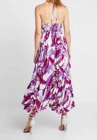 Dlouhé, volné šaty s fialovým a bílým květinovým vzorem. Krajkový korzet a design na krk. Nosené s bílými sandály na podpatku se řemínky.