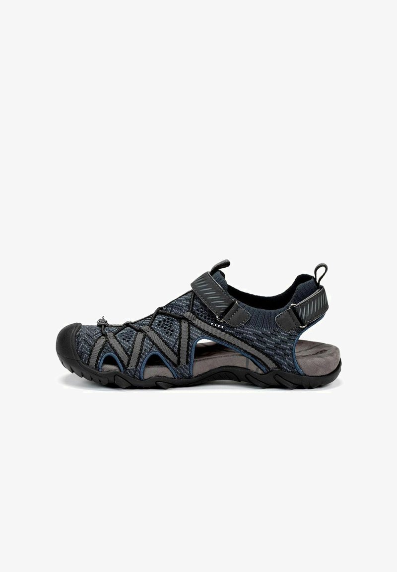 Sandalia negra y gris con parte superior de malla transpirable, correas ajustables, suela texturizada y puntera protectora para actividades al aire libre.