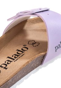 Helllila Slide-Sandale mit einem Korkfußbett, strukturiertem Profil und einem glänzenden Riemen. "Palado"-Logo ist in die Innensohle geprägt.