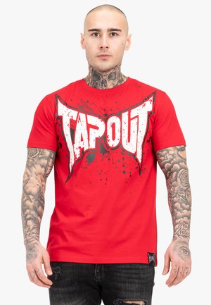 Red cotton t-shirt featuring a large white "TAPOUT" logo with black splatter accents. Short sleeves and a crew neck design.