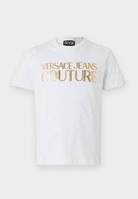 Bílý bavlněný tričko s výrazným zlatým nápisem "VERSACE JEANS COUTURE" na přední straně. Kulatý výstřih a krátké rukávy.