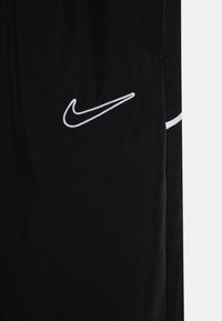 Zwarte sportshorts gemaakt van een gestructureerde stof, met een wit geborduurd Nike-logo en contrasterende zijdetails.
