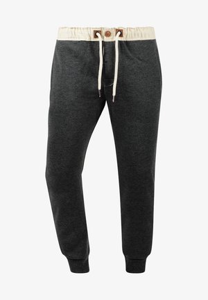 Dark grey sweatpants made of soft fabric, featuring a cream waistband with drawstrings, and tapered legs with elastic cuffs.