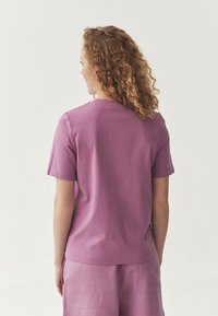 Short-sleeve, round-neck t-shirt in muted purple cotton. Plain design with a relaxed fit, paired with matching pants in the same color.